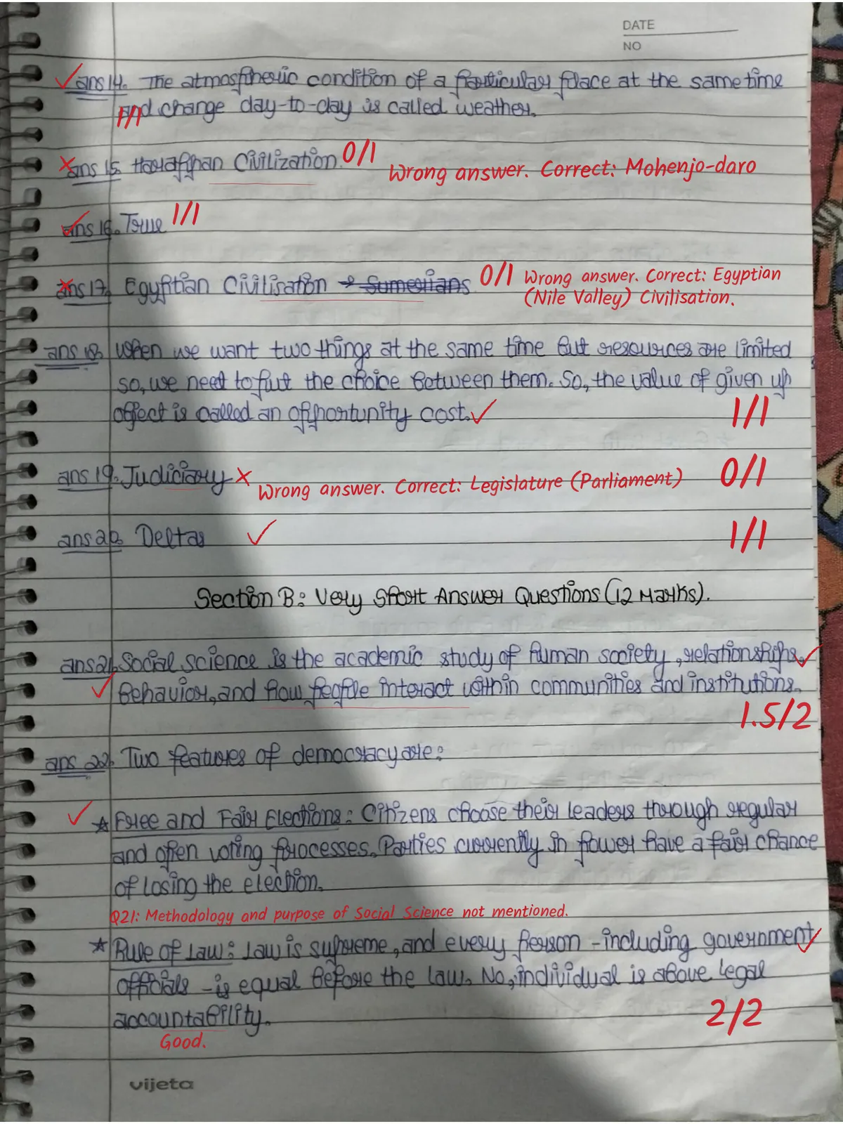 Page two of a checked copy: ticks, a 0/1 with 'Wrong answer. Correct: Mohenjo-daro', 1.5/2 with a note on what the definition missed, and 2/2 with 'Good.'